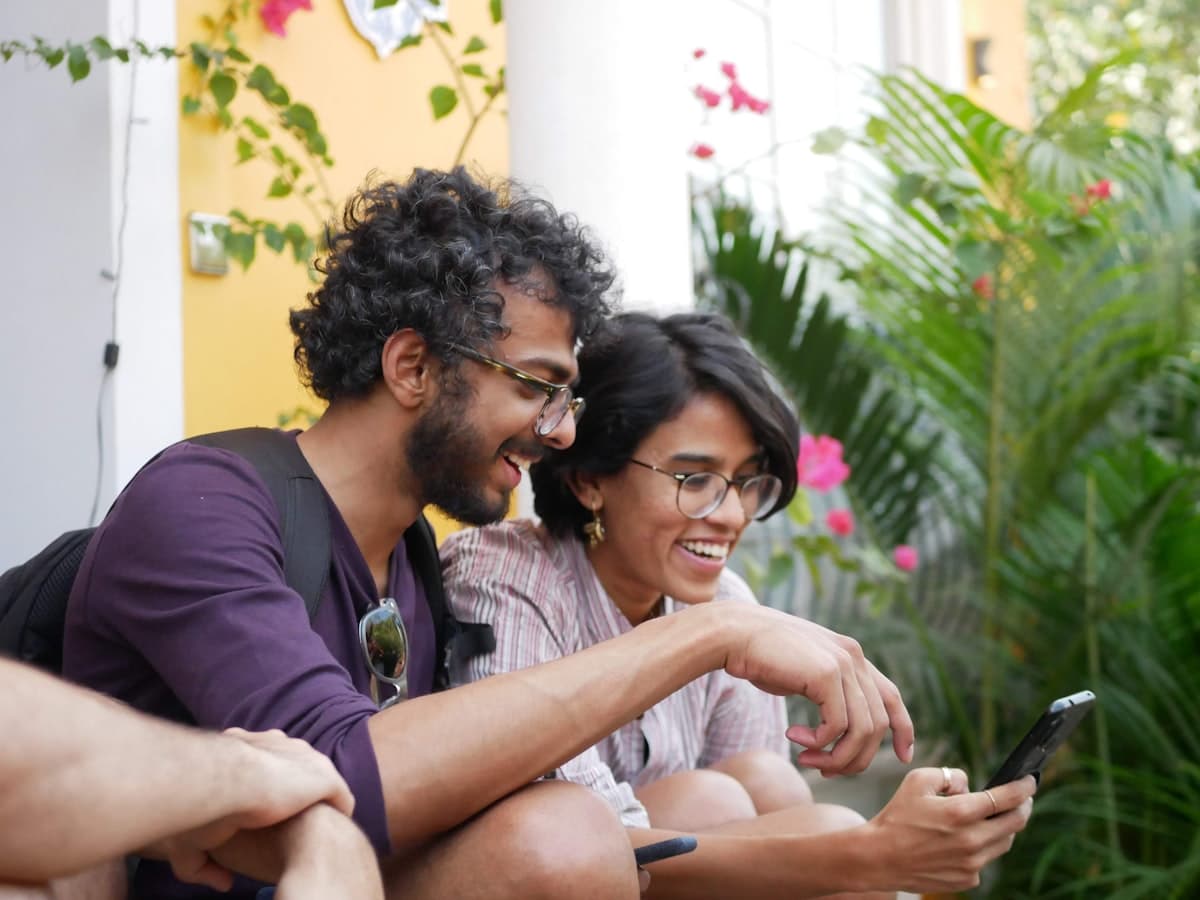 Two friends laughing together while looking at a phone